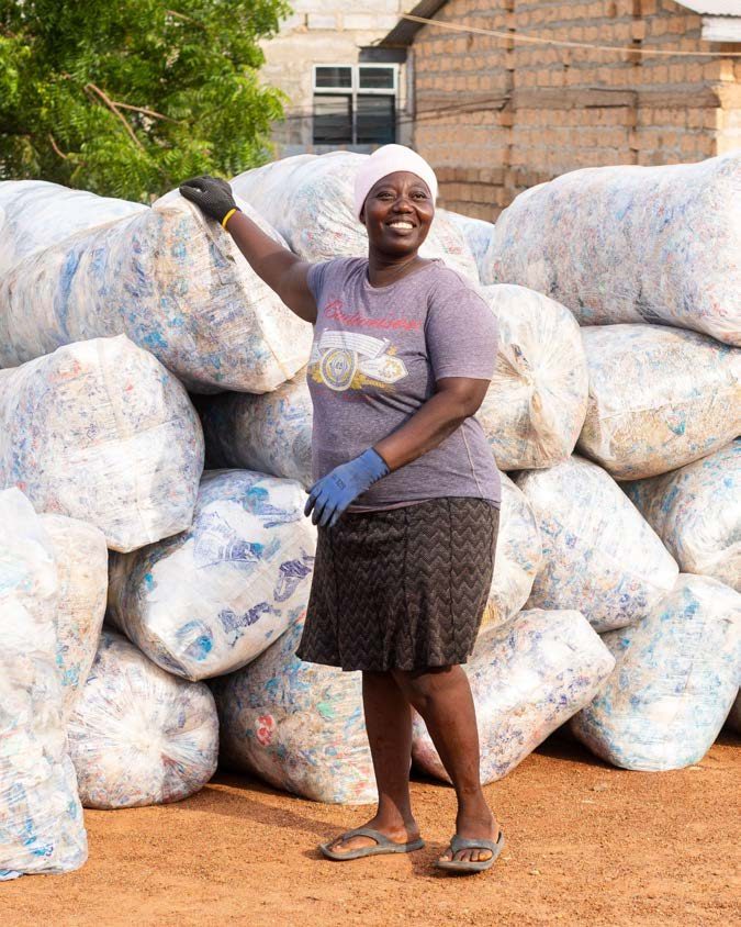 A waste collector at an ASASE Foundation site in Ghana with sacks of collected plastic bottles